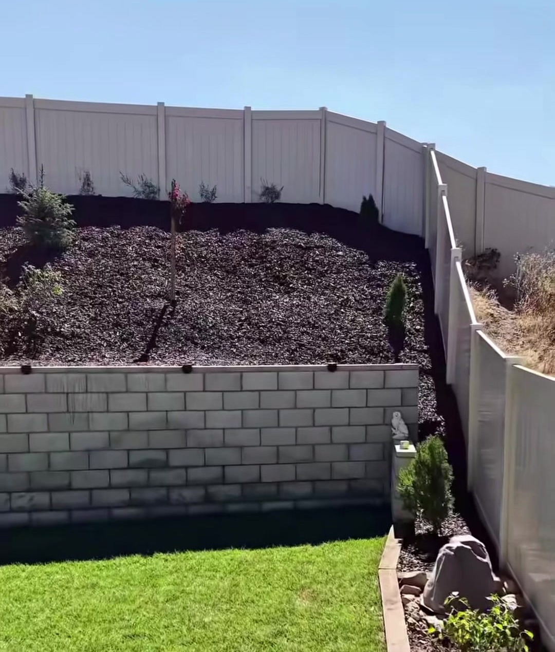 The finished job: green sod, a block wall and fresh mulch on the slope